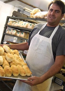 man in white apron holding a tray of pepperoni rolls