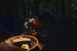 man with head lamp starting a campfire