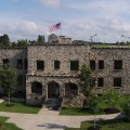 large hand-cut stone building with American flag in the background