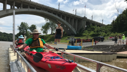 people in a red canoe getting into the river using a kayak/canoe launch