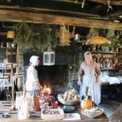 2 women dressed in 18th century clothes demonstrating how to cook in an open fire