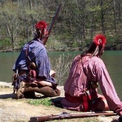 2 Native Americans sitting along the river bank