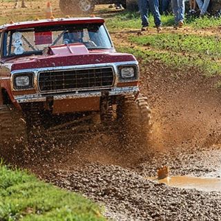 red truck driving through a mud pit