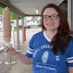 Dark haired woman in blue t-shirt holding a very large chocolate ice cream cone