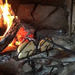 toasting bread in front of a hearth fire
