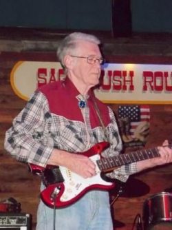 man in red western shirt holding a guitar
