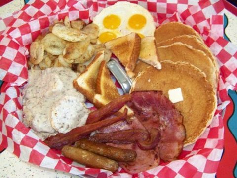 pancakes, sausage, bacon, eggs, toast, sausage gravy & biscuits and fried potatoes served in the lid of a trash can