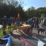 people holding canoes, kayaks and paddles getting ready for a race