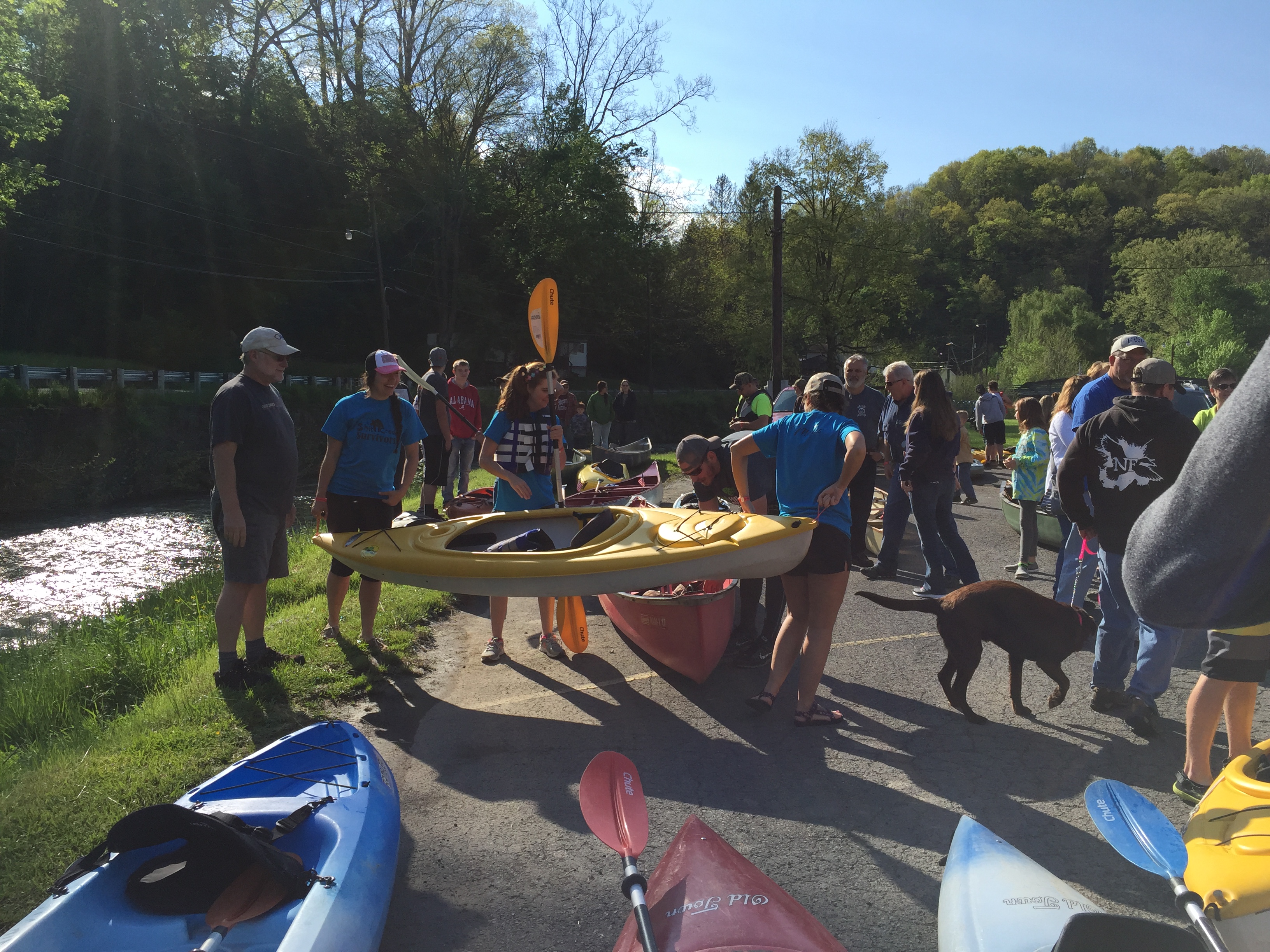 people holding canoes, kayaks and paddles getting ready for a race