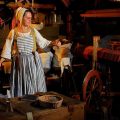 woman dressed in 18th century clothes spinning yarn