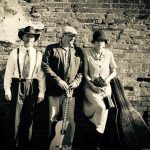 2 men and 1 woman dressed in 1920s clothes holding instruments