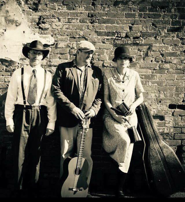 2 men and 1 woman dressed in 1920s clothes holding instruments