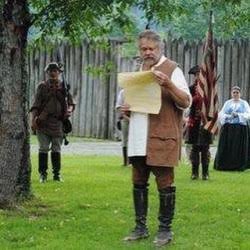 man in frontier costume holding a cream-colored document