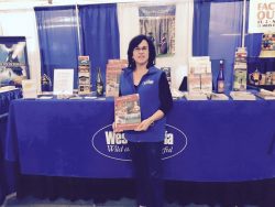 woman standing in front of a table holding a brochure