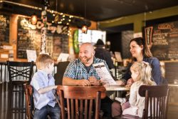 man and woman and 2 kids sitting in a restaurant looking at a menu