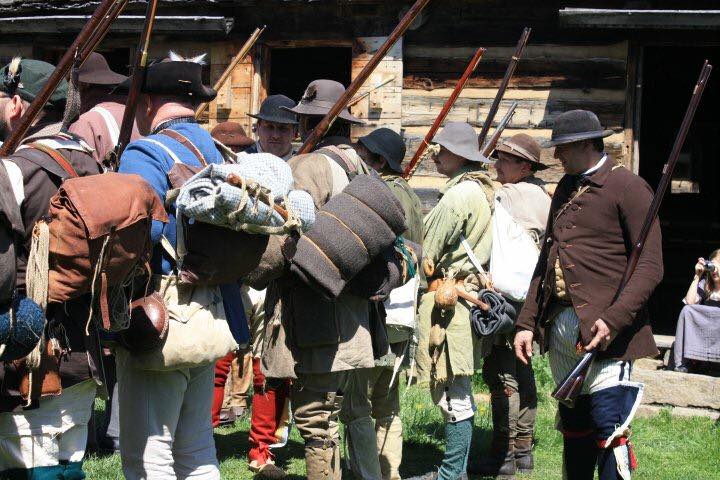 men dressed in 18th century clothes with rifles