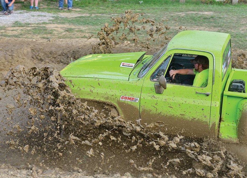green truck driving through mud