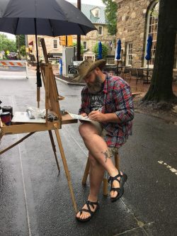 man painting at an easel outdorrs