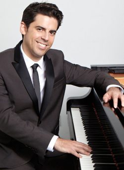 man sitting at a piano with hand on keys