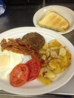 plate of eggs over easy, bacon, tomato slices, hash browns, sausage patty and toast