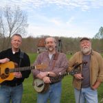 3 men standing outside holding guitars, and banjo