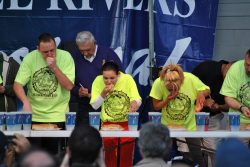 men and women in green t-shirts in food eating contest