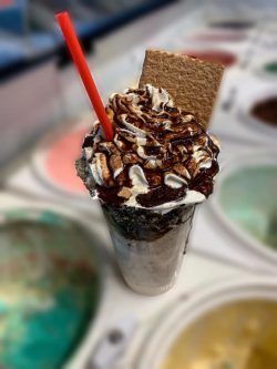 milkshake with whipped cream and chocolate sauce with a whole graham cracker