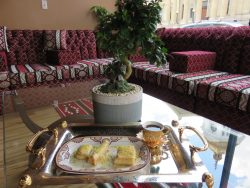a tray of three desserts and a cup of coffee with a plant in the background and a red sectional couch