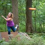 woman disc golfing surrounded by trees