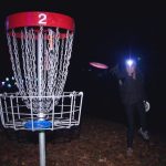 person with head lamp playing disc golf
