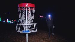 person with head lamp playing disc golf