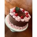chocolate layer cake decorated with pink icing and fresh strawberries