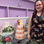 woman in floral print shirt standing by decorated layer cakes