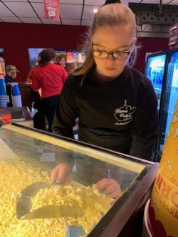 girl scooping out popcorn at a movie theater