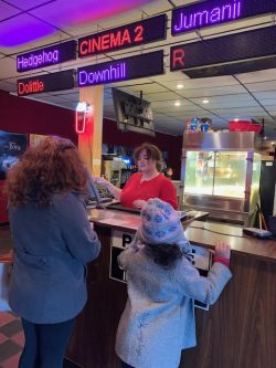 woman and child standing at a ticket counter at a movie theater