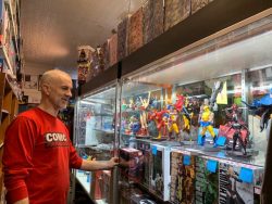 man in red shirt and jeans standing in front of a glass display case of action figures
