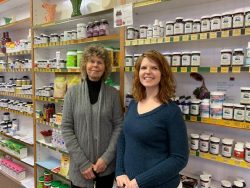 2 women standing in front of shelves of vitamins 