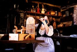 woman dressed in 18th-century clothes weaving
