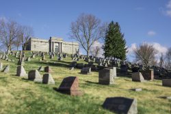 headstones at a cemetery with an abby in the background