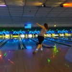 woman bowling with lights glowing in lanes