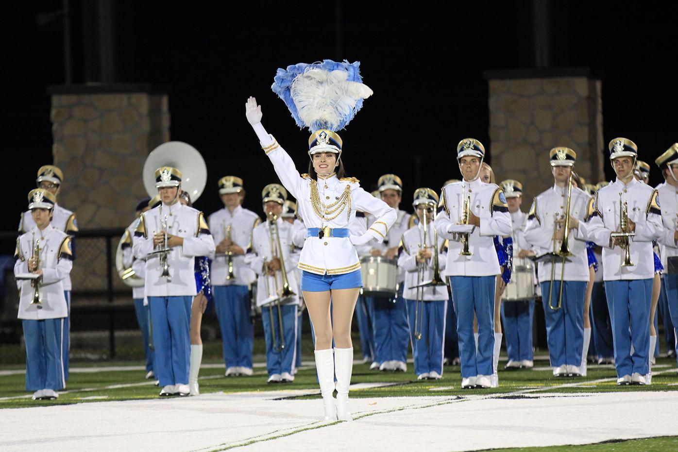marching band dressed in white and blue uniforms led by the drum major