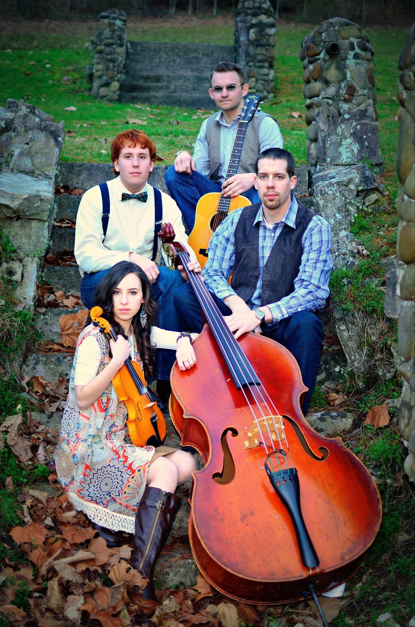 four people setting on steps with a large cello