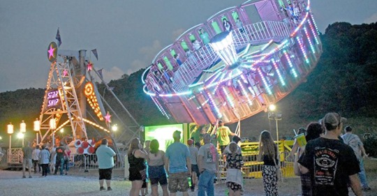 people standing around carnival rides