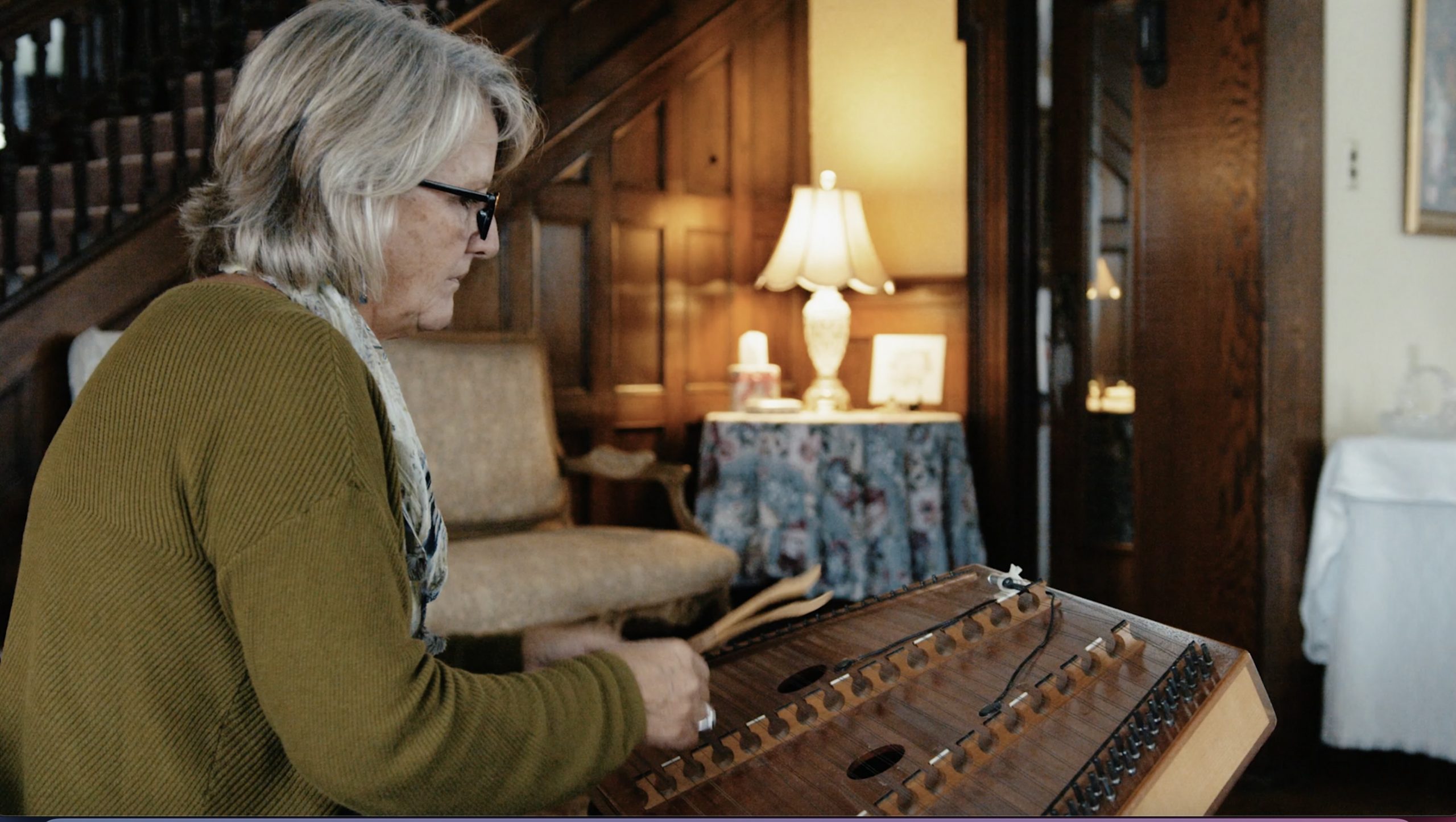 woman in green sweater playing a hammered dulcimer