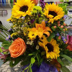 fresh flower arrangement with sunflowers, orange lilies and roses.