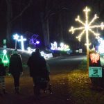 people walking through Christmas lights