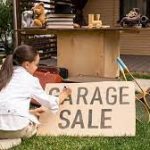 young girl making a sign on cardboard for a garage sale