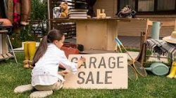 young girl making a sign on cardboard for a garage sale