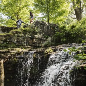 man and woman hiking over waterfalls