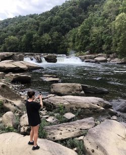 woman taking a photo of waterfalls